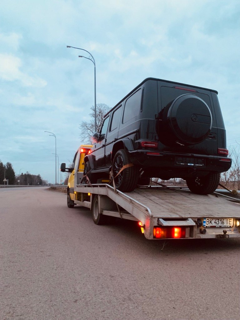 Жовтий евакуатор перевозить чорний Mercedes G-Class